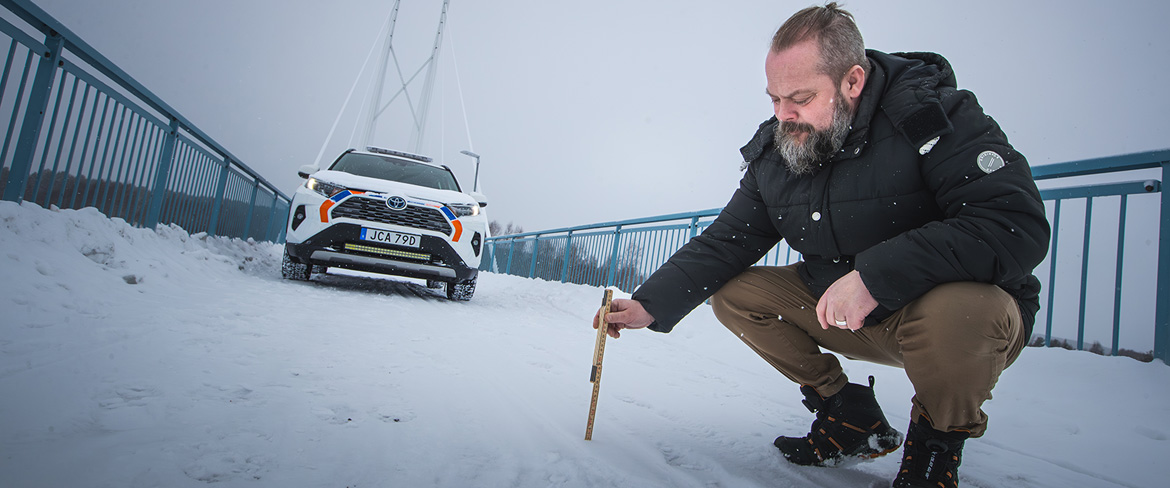 Daniel mäter snömägden på gång- och cykelbro.