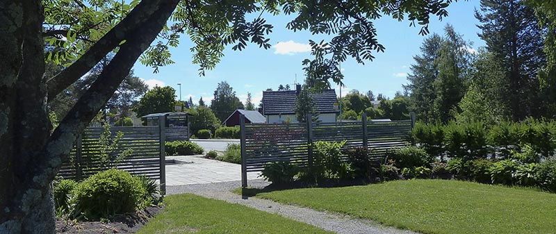 Vy över parken med grusgång, skärmväggar och planteringar.