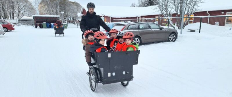 På väg ut på äventyr. Pedagogen Patrik Larsson har lastat sex glada barn i vagnen/lådan på sin elcykel, vilket får barnen att stråla av förväntan.